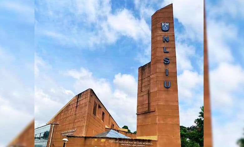 NLSIU campus building with blue sky and clouds, featuring the university's name on a tall tower.