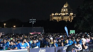 Thousands of marathon runners gather at the starting line in Hyderabad at night.