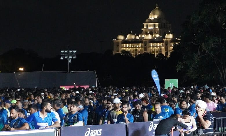 Thousands of marathon runners gather at the starting line in Hyderabad at night.