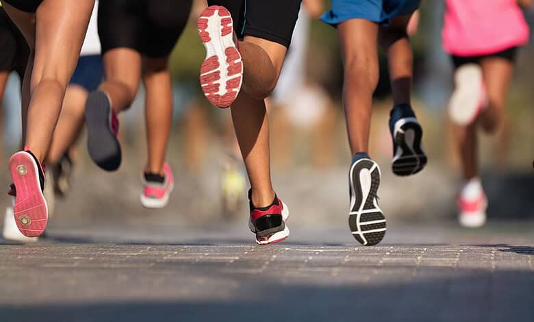 Group of runners participating in a marathon, focusing on their running shoes and legs.