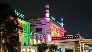 Colorfully lit mosque at night with vibrant green, pink, and purple lights.