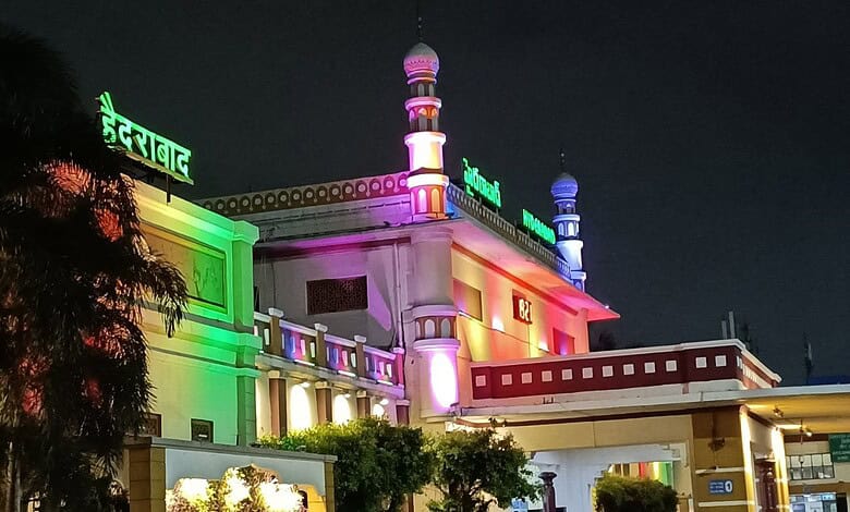 Colorfully lit mosque at night with vibrant green, pink, and purple lights.