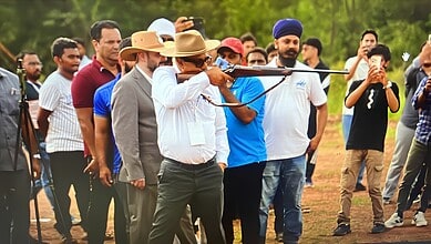 Hyderabad man shooting with a rifle during a public event, surrounded by spectators.