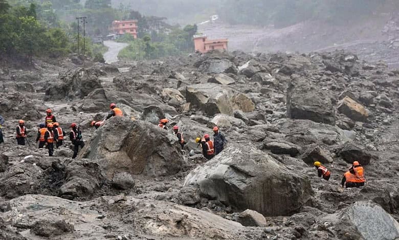 Rescue workers in orange vests search through debris after Nepal floods.