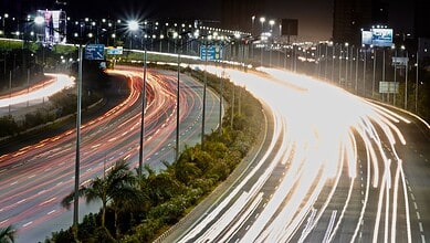 Long exposure of busy highway at night with light trails from vehicles in Hyderabad, Telangana.