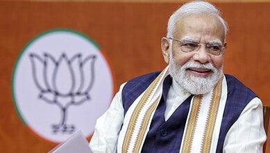 Prime Minister Narendra Modi smiling during Khelo India sports event with BJP logo in background.