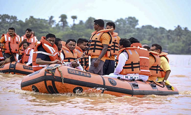 Rescue team in orange life jackets evacuates people by boat during Odisha flood.