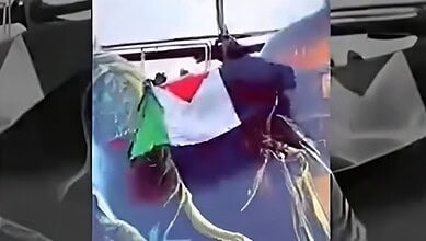 Person holding Palestinian flag on boat during sunset in Shivamogga.