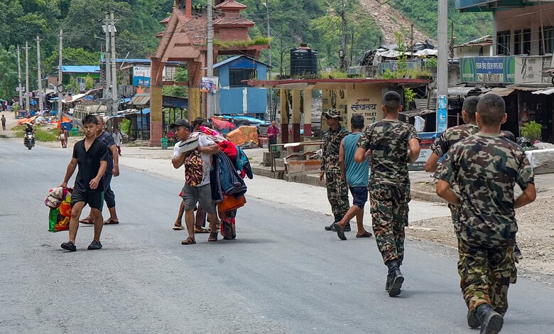 People carry essentials as they move to safer locations after authorities issued a fresh flood warning following a rise in water levels in areas affected by a devastating flash flood earlier this