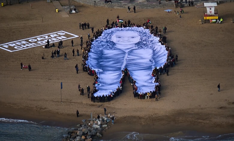 People hold a giant portrait of Hind Rajab, a five-year-old Palestinian girl who was killed during the war in Gaza, on a beach in Barcelona, Spain, Thursday, January 29, 2026.