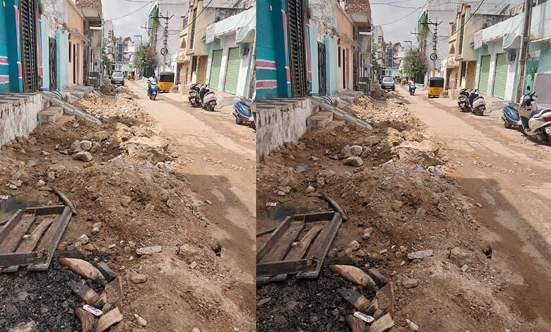 Uneven road under construction in Hyderabad with buildings on both sides.