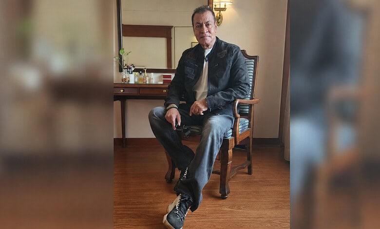 Bollywood actor Pradeep Rawat sitting on a chair in a room with wooden flooring.