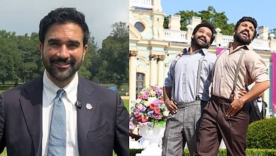 Two men smiling outdoors, one in a suit and the other in casual attire, with a historic building in the背景.