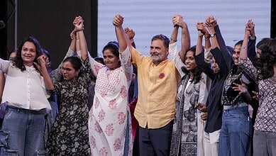 Indian politician Rahul Gandhi with supporters at a rally, raising their hands in unity.