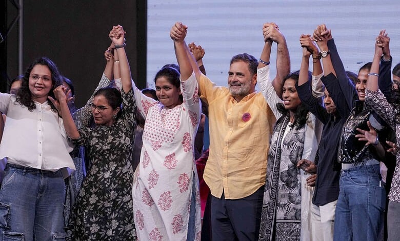 Indian politician Rahul Gandhi with supporters at a rally, raising their hands in unity.