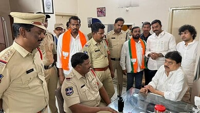 Police officers and officials in a meeting with a man in a white shirt at a desk.
