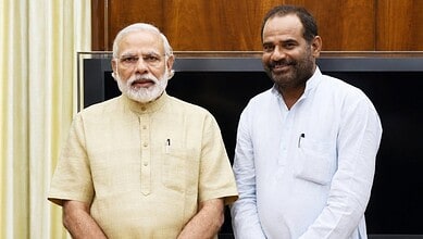 Indian Prime Minister Narendra Modi with a man in a white shirt, smiling, indoors.