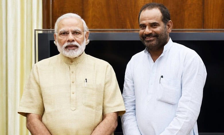 Indian Prime Minister Narendra Modi with a man in a white shirt, smiling, indoors.