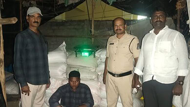 Group of four men standing near large sacks and a green laser device at night.