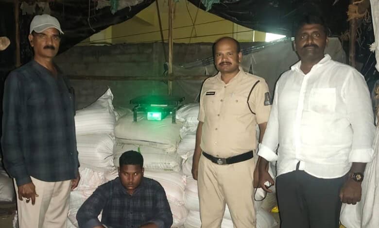 Group of four men standing near large sacks and a green laser device at night.