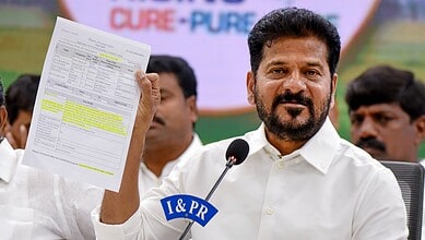 Revanth holding a document during a public event, speaking into a microphone.