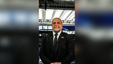 Roberto Carlos smiling at a Moroccan wedding, wearing a black suit and tie.