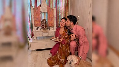 Sara Ali Khan celebrates Rakhi with brother, holding a plate of sweets and a dog nearby.