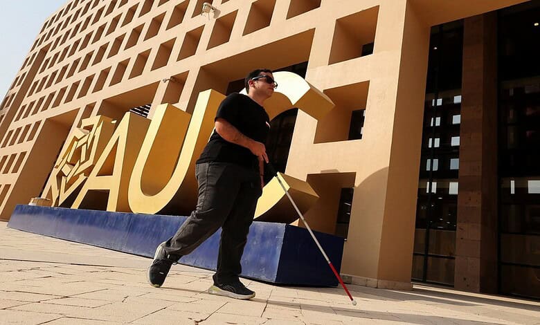 Blind Egyptian man with white cane walking past a modern building with large yellow letters.