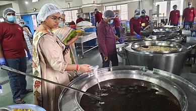 Women inspecting large pots of boiling liquid at a food processing unit in Hyderabad.