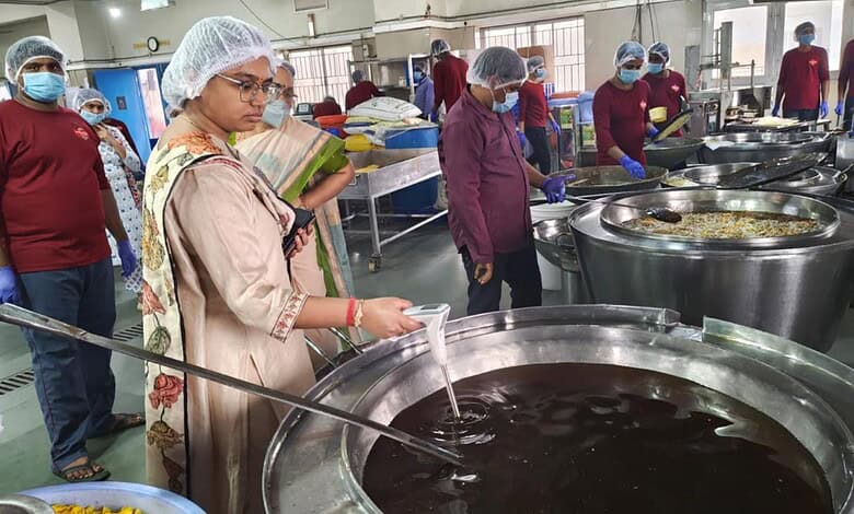 Women inspecting large pots of boiling liquid at a food processing unit in Hyderabad.