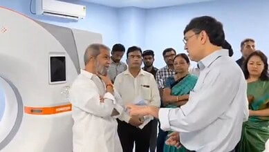 Doctor and senior man shaking hands near medical imaging device with onlookers.
