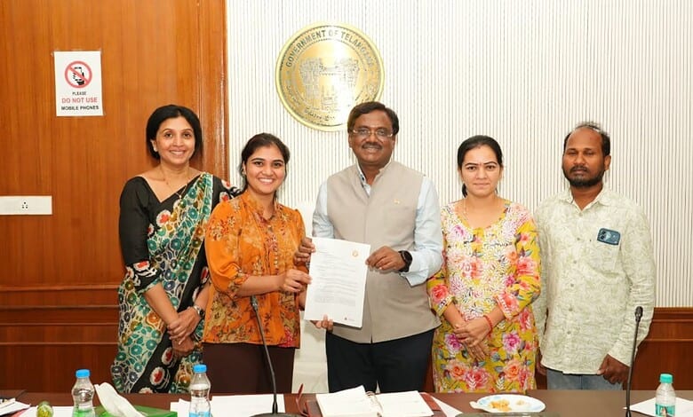 Group of five people at TOMCOM signing event, smiling and holding a document.