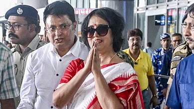 Taslima Nasrin at an airport, surrounded by security and onlookers.