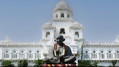 Statue of Mahatma Gandhi in front of a historic white building in India.