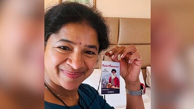 Woman holding a card with a photo of a man wearing a mask, smiling at the camera.