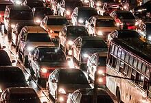 Traffic congestion in Hyderabad during evening rush hour with many cars and a bus on wet roads.