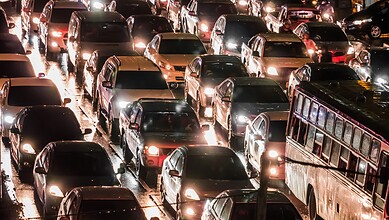 Traffic congestion in Hyderabad during evening rush hour with many cars and a bus on wet roads.