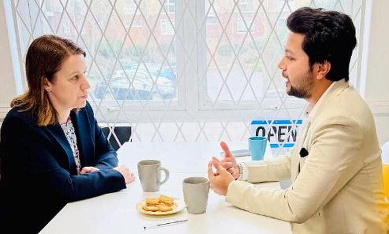 Two individuals engaged in a serious conversation at a table with coffee cups and snacks.