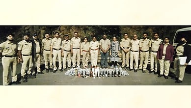 Police officers display seized liquor bottles near Pahadishareef in Hyderabad.