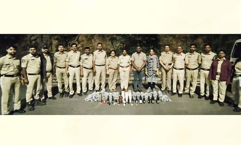 Police officers display seized liquor bottles near Pahadishareef in Hyderabad.