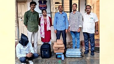 Police officers and a suspect with seized 14 kg ganja in front of a police station.