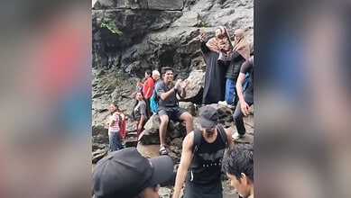 Group of people at Naneghat Reverse Waterfalls, some taking photos and exploring the rocky area.