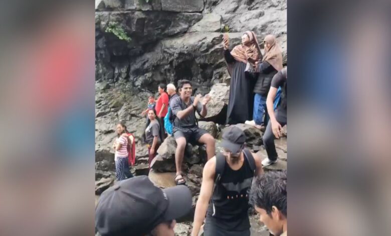 Group of people at Naneghat Reverse Waterfalls, some taking photos and exploring the rocky area.