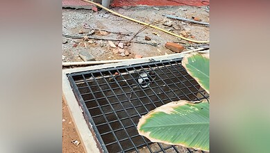 Drain cover with a black grate installed on a construction site.