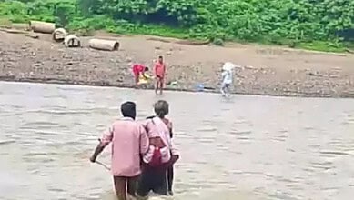 Man carries mother through flooded stream in Asifabad district