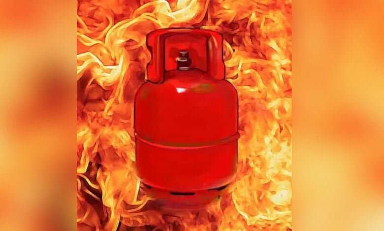 Red LPG cylinder surrounded by flames during a fire incident.