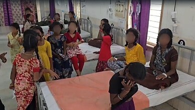 Group of children in hospital ward, some sitting on beds, others standing, wearing colourful clothes.