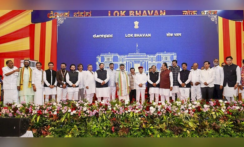 Group of Karnataka ministers and officials on stage during cabinet induction ceremony.