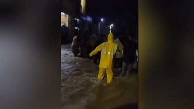 Rescue operation during floods with people wading through water at night.