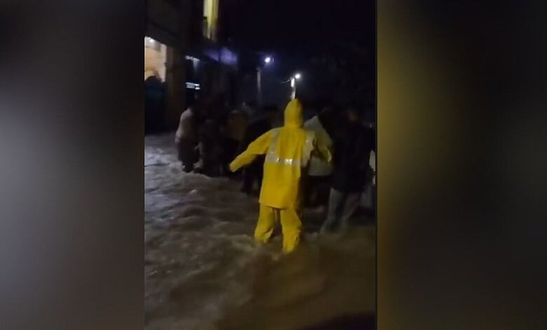 Rescue operation during floods with people wading through water at night.